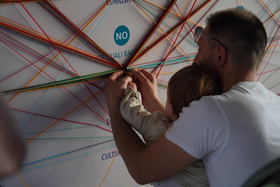 installazione 2024: padre e figlia infilano il filo di lana nell'anello con la loro risposta