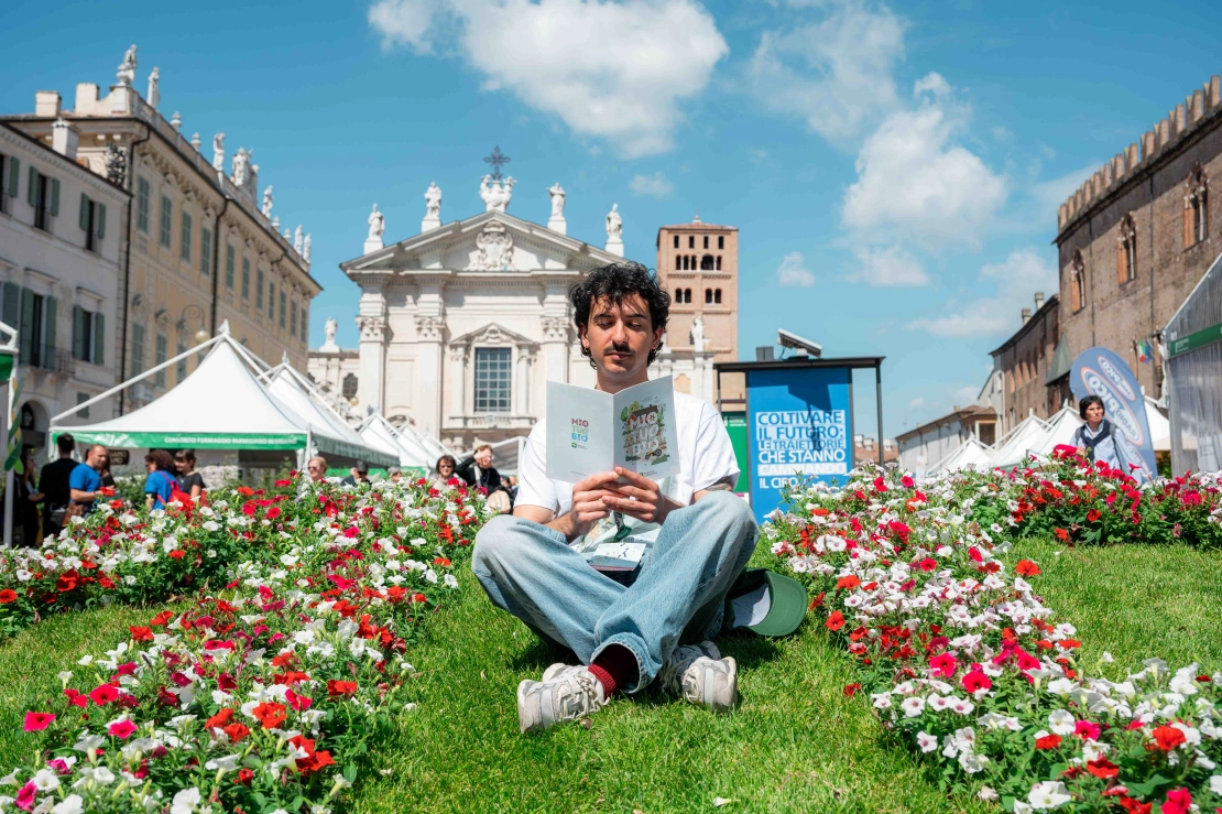 volontario del festival seduto sull'aiuola del decennale in piazza Sordello